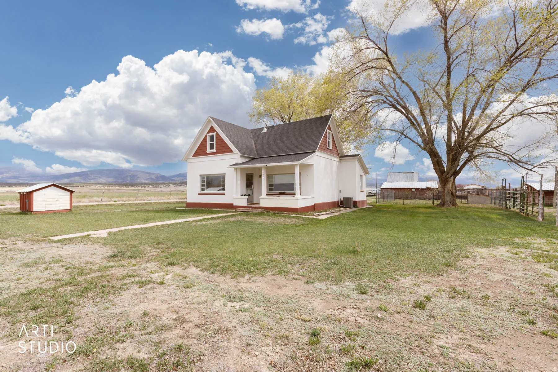 Bungalow-style home featuring covered porch, a shingled roof, a storage unit, and a mountain view