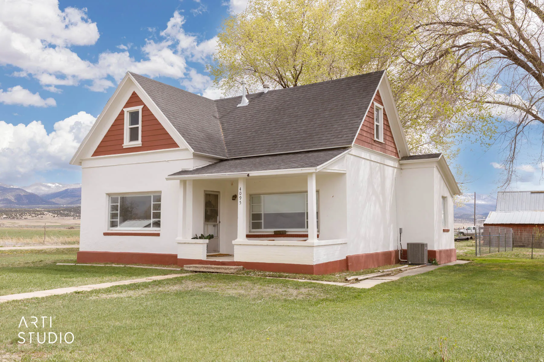 View of front facade featuring roof with shingles, a porch, a front yard, and a mountain view