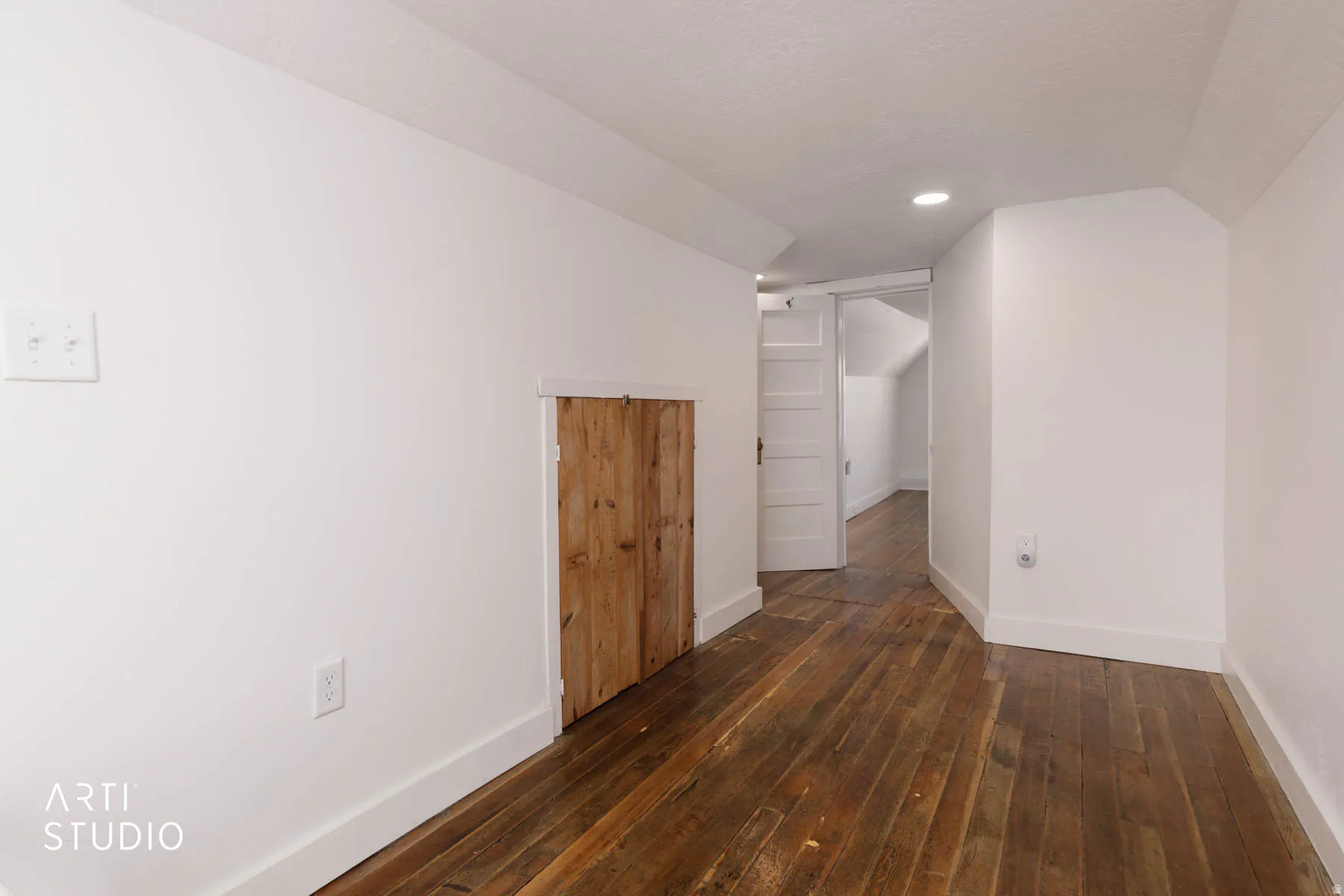 Spare room featuring dark wood-style floors and lofted ceiling