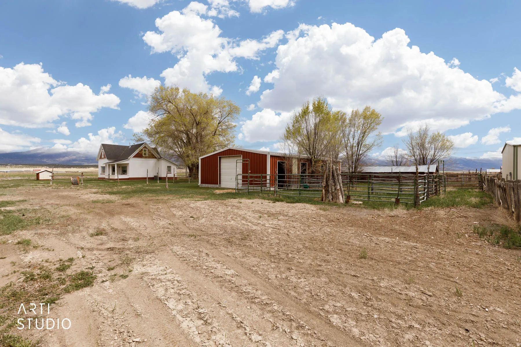 View of yard featuring an outdoor structure, a detached garage, a rural view, dirt driveway, and an exterior structure
