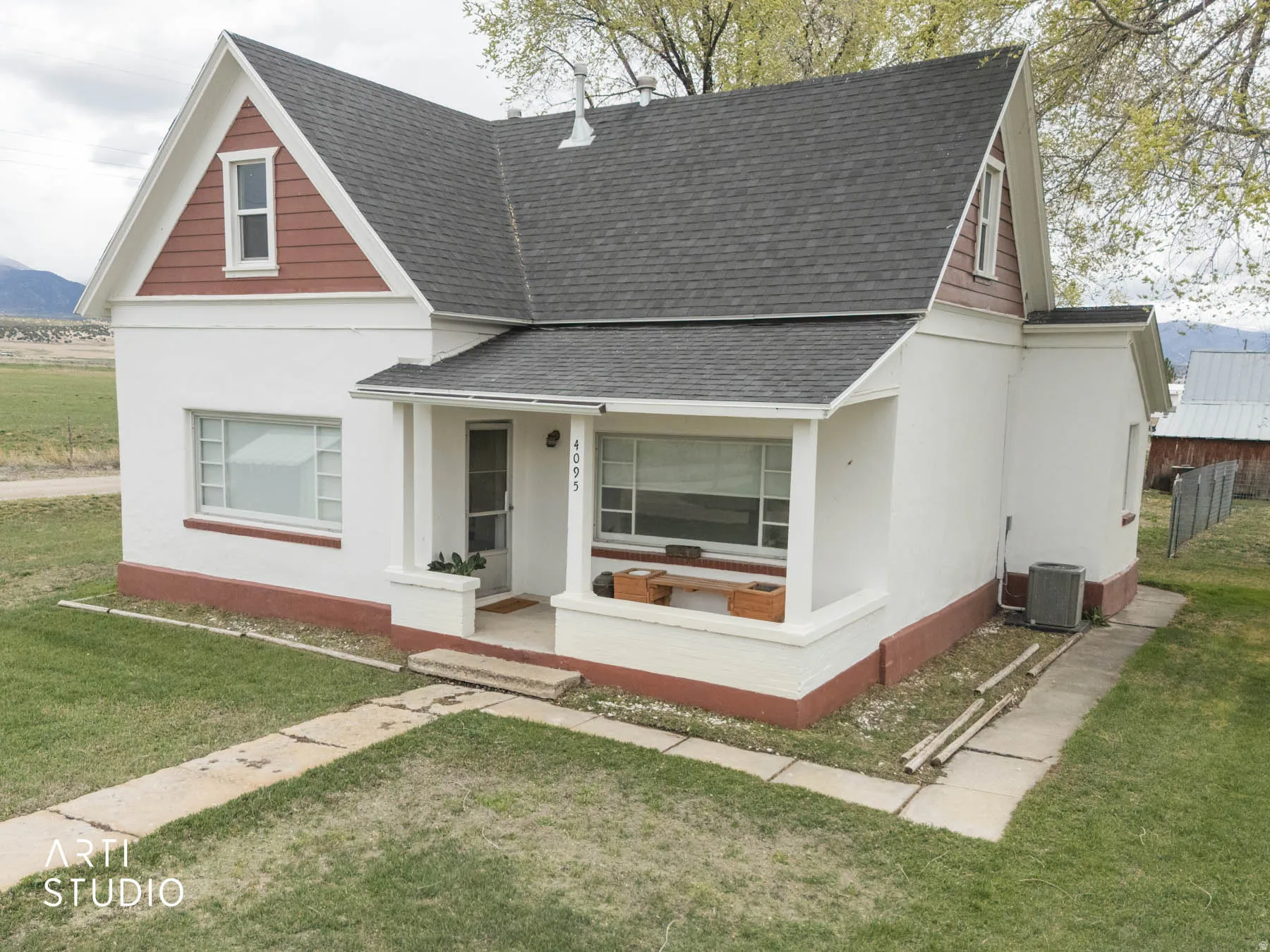 View of front of property featuring a shingled roof, a front yard, covered porch, and stucco siding
