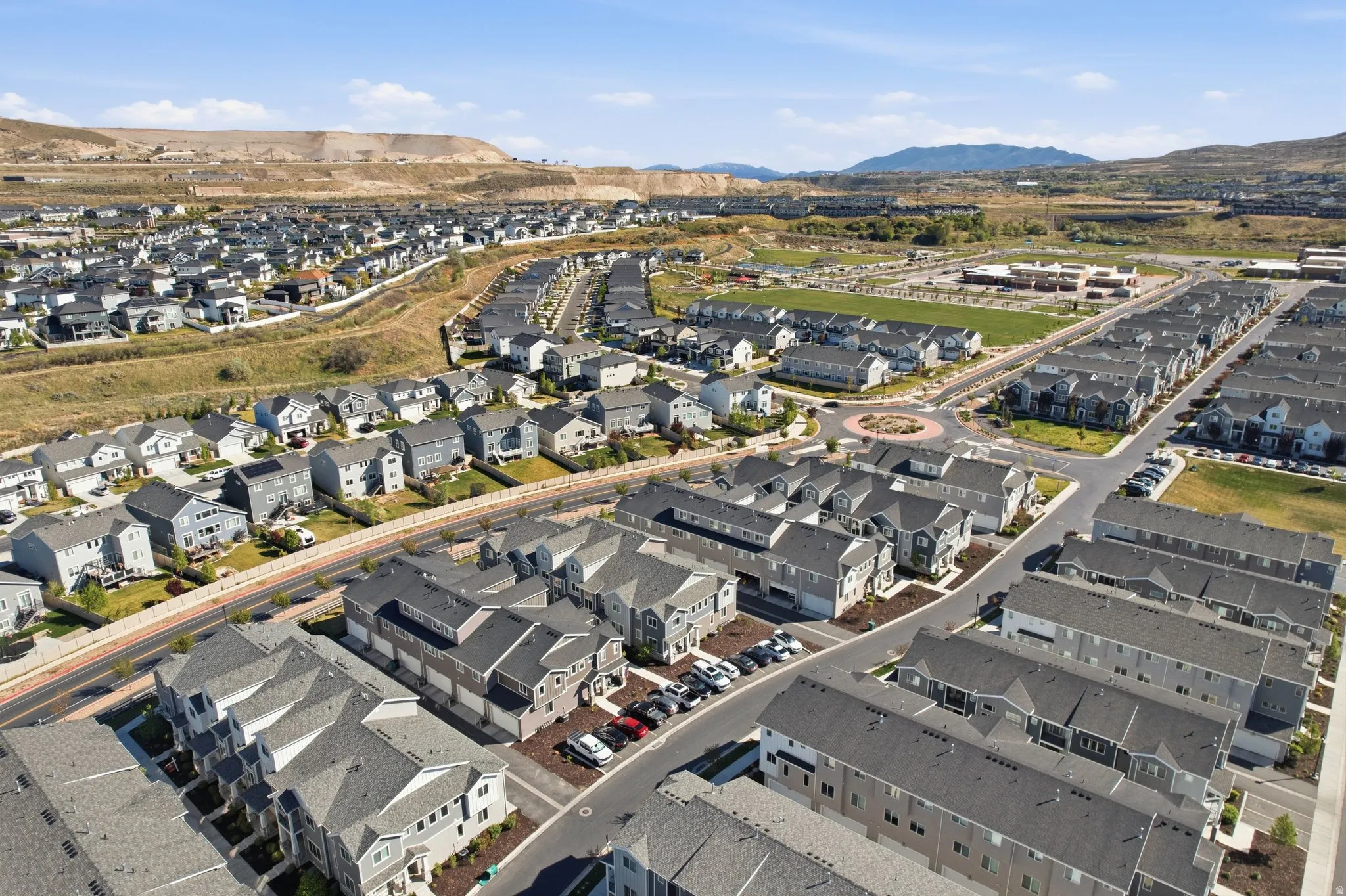 Aerial view of property and surrounding area featuring a mountain backdrop and nearby suburban area