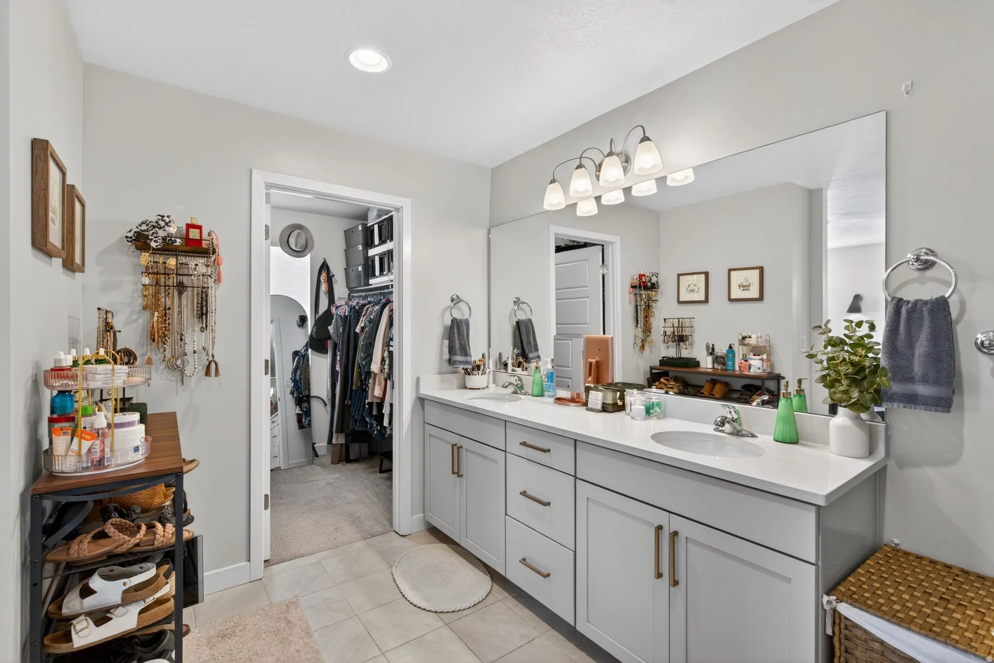 Full bath with double vanity, a spacious closet, and light tile patterned floors