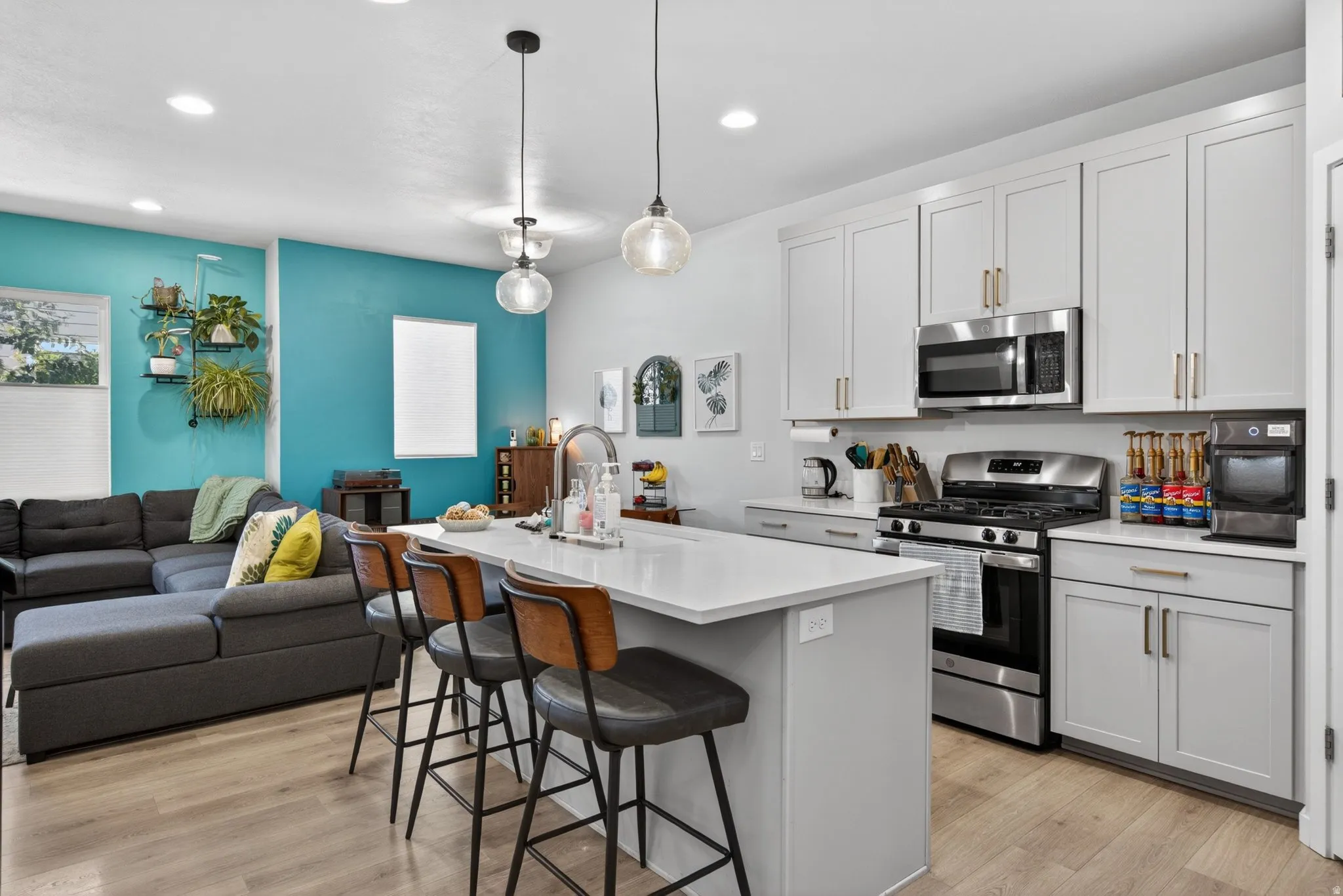 Kitchen featuring stainless steel appliances, open floor plan, a breakfast bar area, a kitchen island with sink, and light wood-type flooring