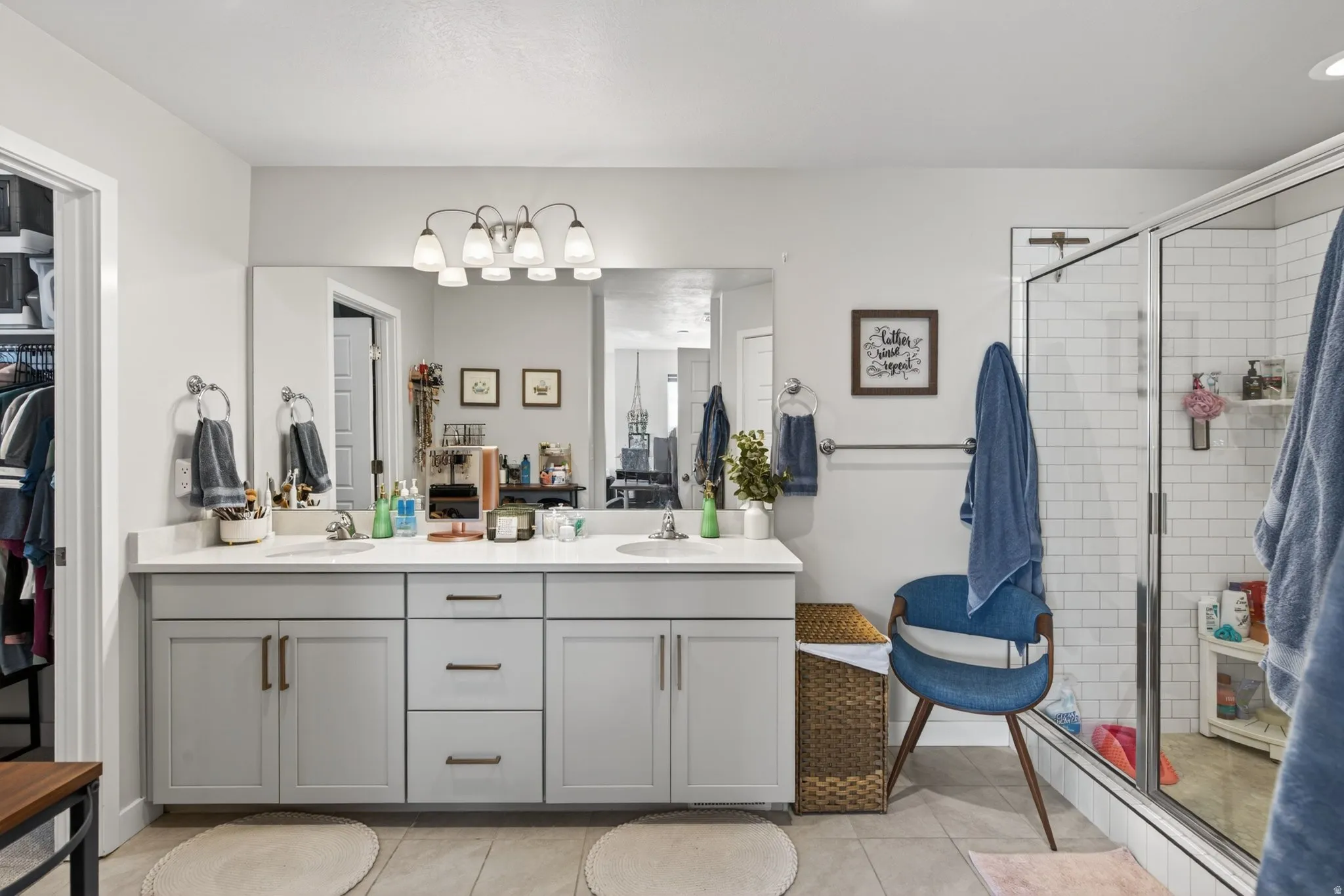 Bathroom featuring double vanity, a stall shower, light tile patterned floors, and a spacious closet