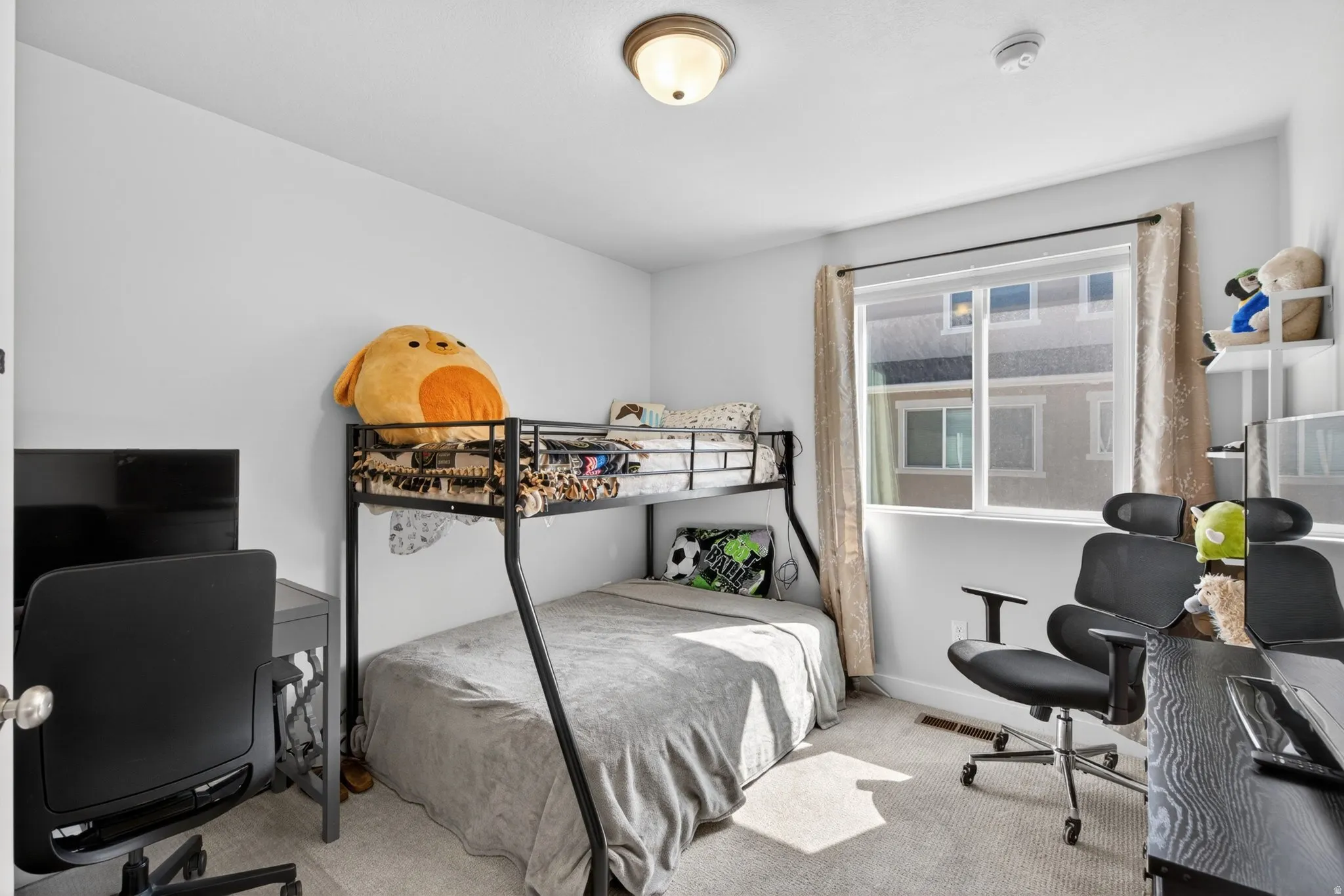 Bedroom featuring light colored carpet and a desk