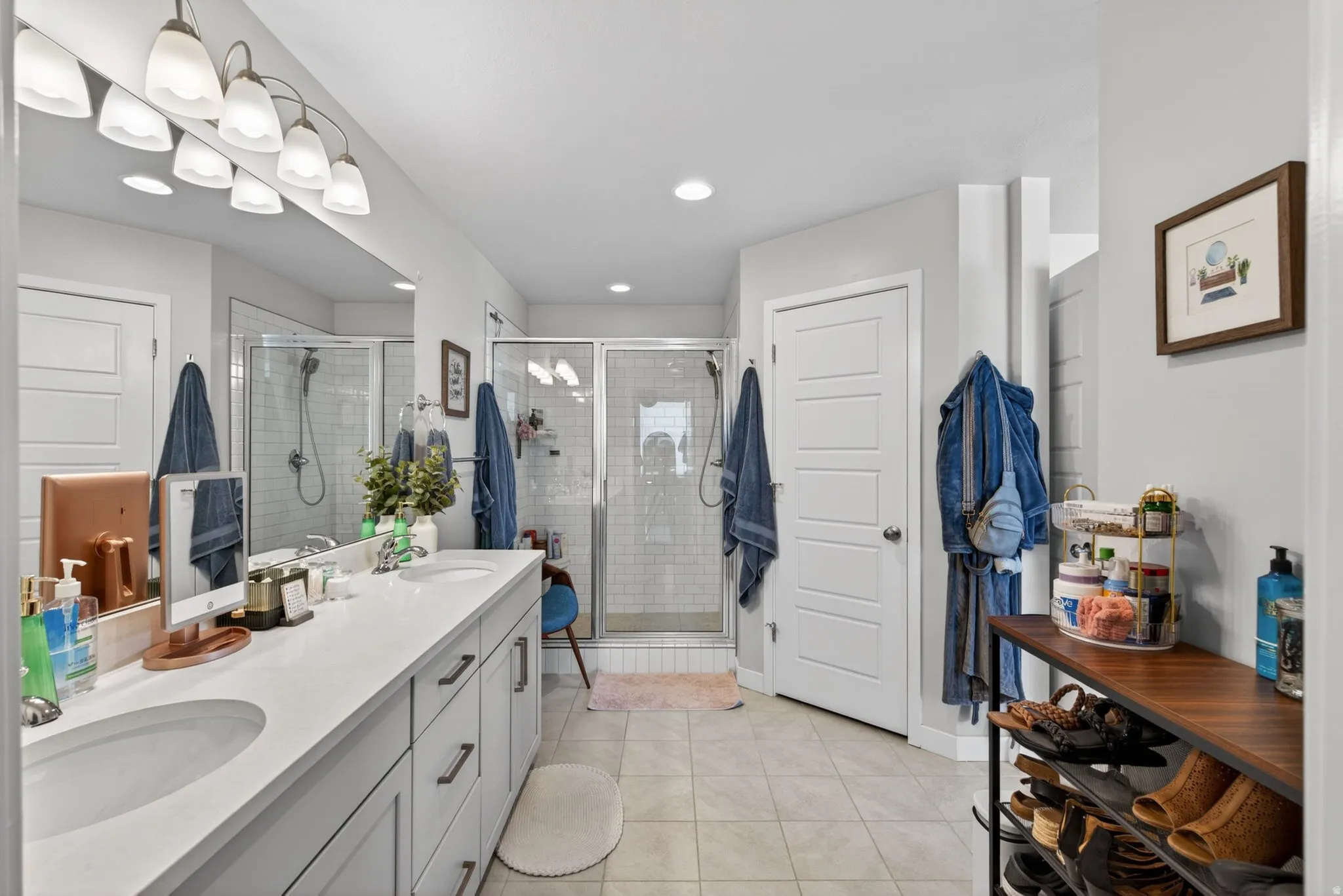 Bathroom with double vanity, light tile patterned floors, and a stall shower