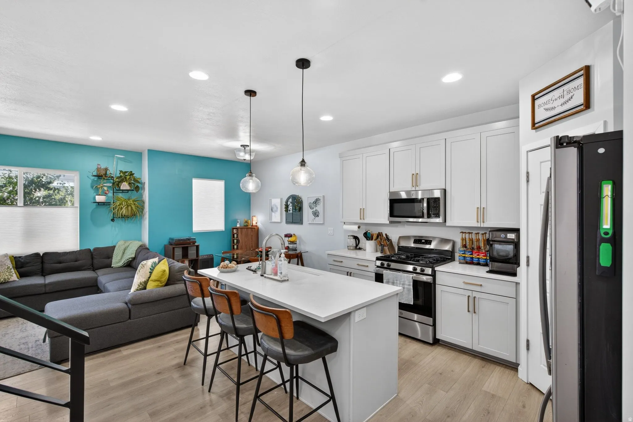 Kitchen with stainless steel appliances, an island with sink, a breakfast bar, open floor plan, and light wood-type flooring
