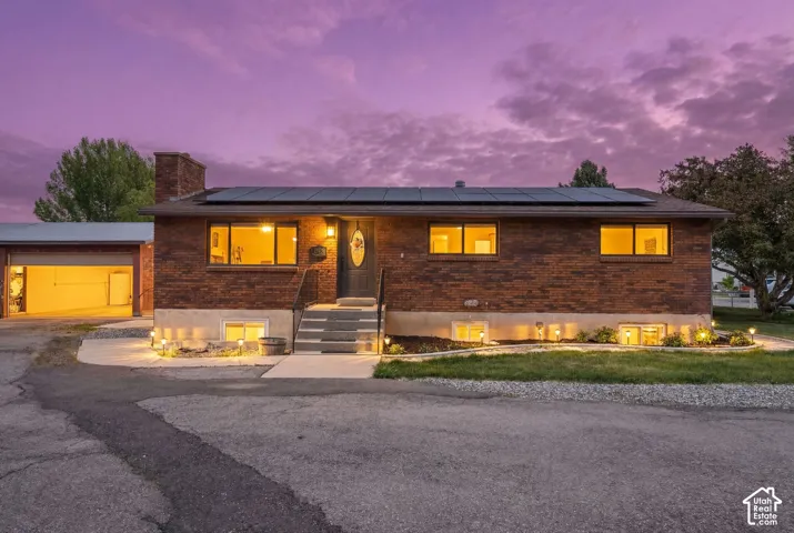 Ranch-style home featuring brick siding, roof mounted solar panels, and a chimney
