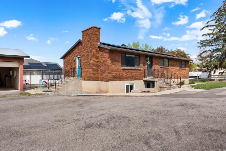 View of front of property featuring roof mounted solar panels, brick siding, and a chimney