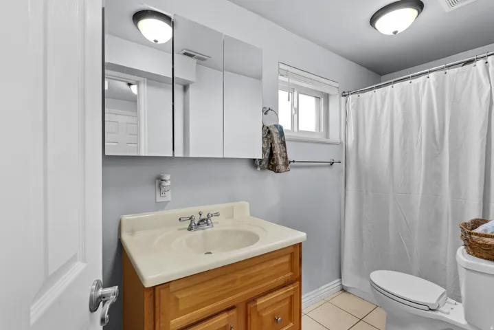 Bathroom with curtained shower, vanity, and light tile patterned flooring