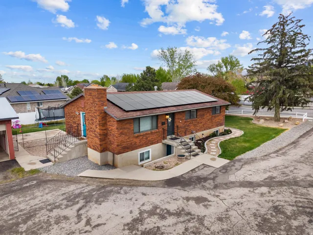 View of front facade with solar panels, brick siding, and a front yard