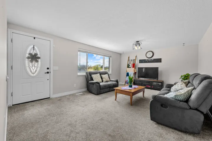 Living area featuring light carpet and a textured ceiling