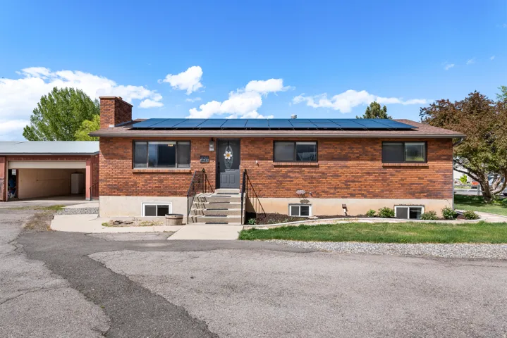 Ranch-style home featuring brick siding, roof mounted solar panels, and a chimney