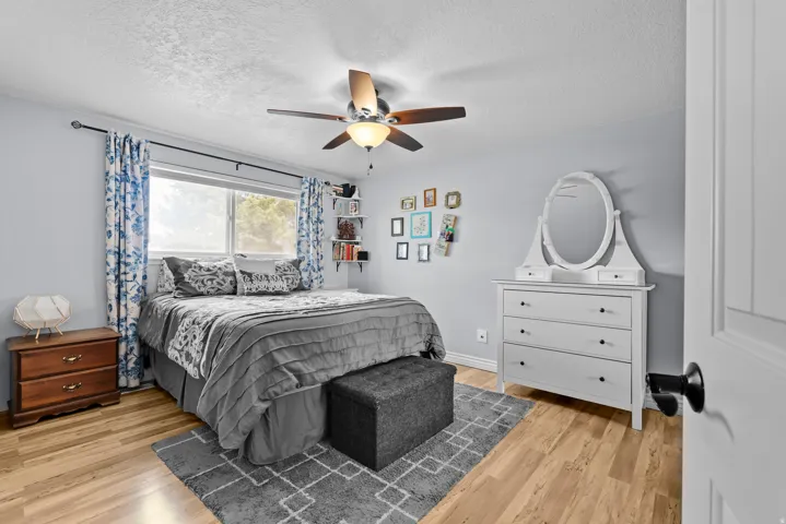 Bedroom featuring a ceiling fan, light wood-style floors, and a textured ceiling