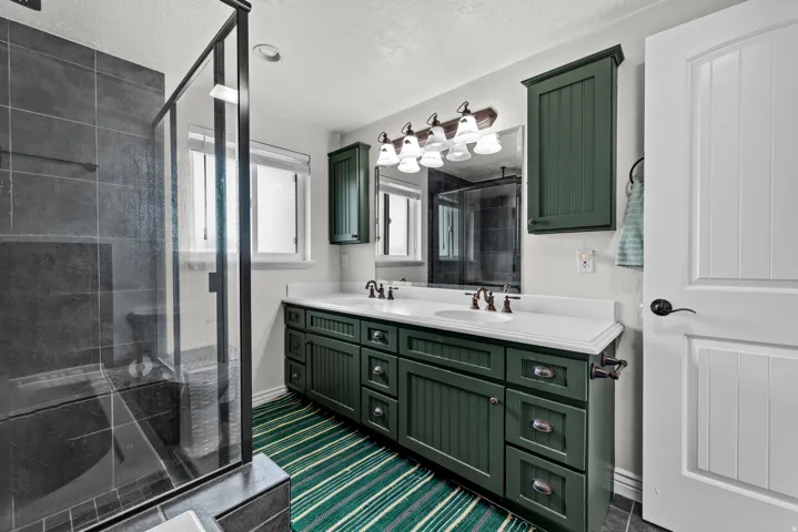 Full bath with double vanity, a stall shower, and a textured ceiling