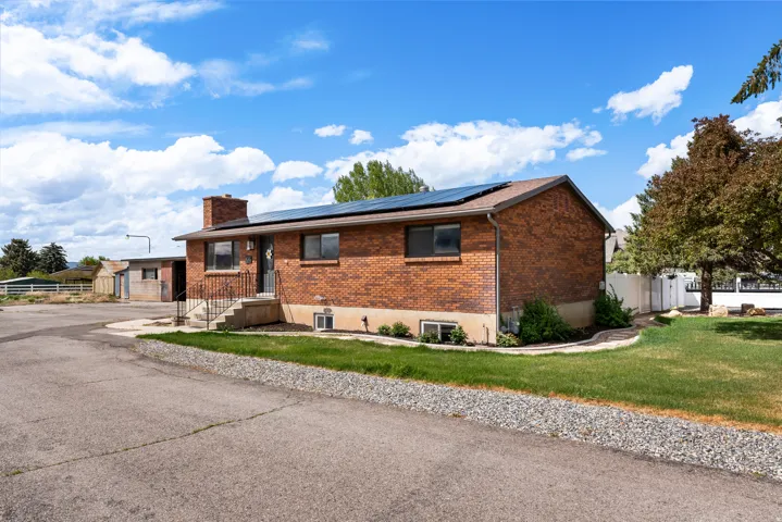 Ranch-style house with brick siding, solar panels, and a chimney