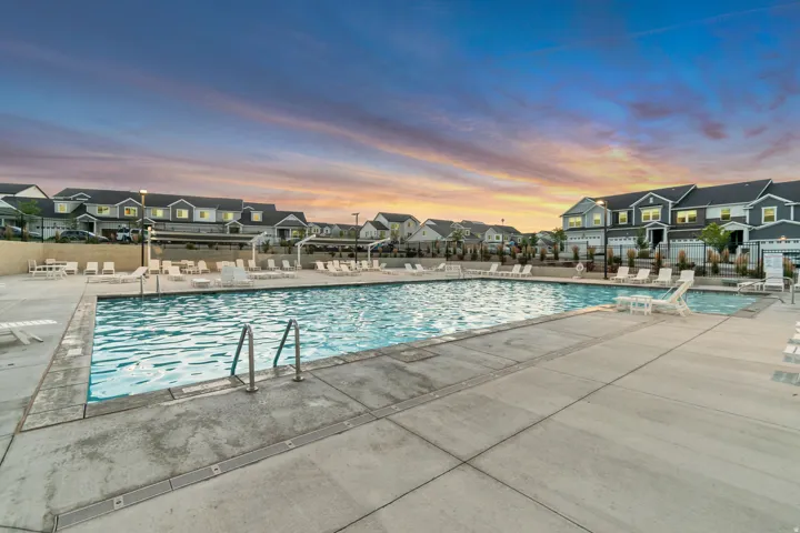 Pool at dusk with a residential view, a community pool, and a patio