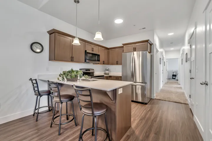 Kitchen featuring stainless steel appliances, light countertops, a breakfast bar, dark wood finished floors, and a peninsula