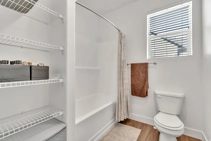 Bathroom featuring light wood-style flooring, shower / tub combo with curtain, and a closet