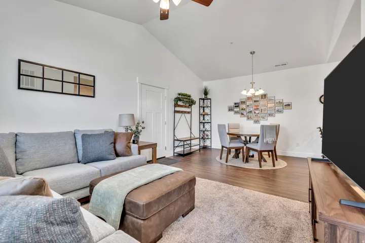 Living room with ceiling fan, vaulted ceiling, wood finished floors, and hanging lights