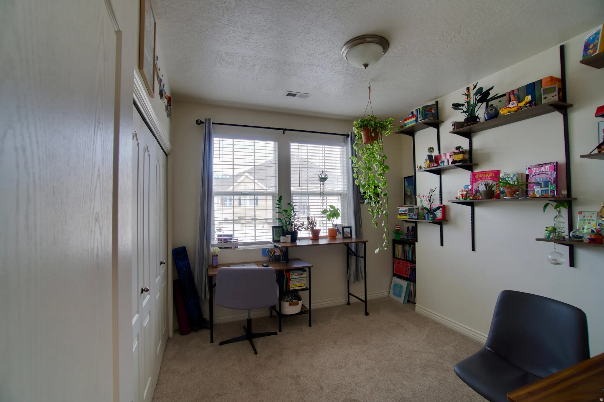 Office with a textured ceiling and light colored carpet