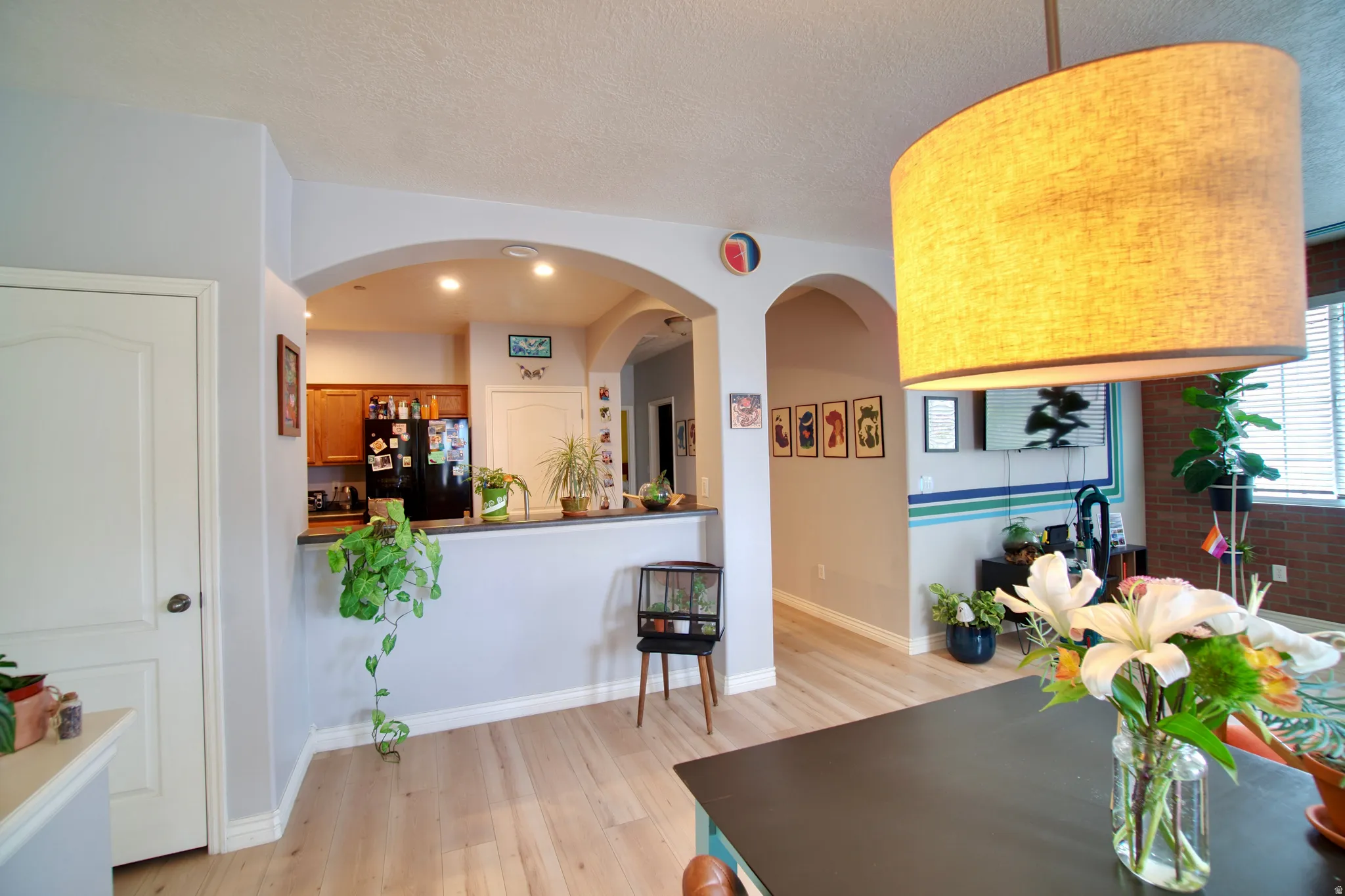 Dining space featuring light wood-type flooring, a textured ceiling, and arched walkways