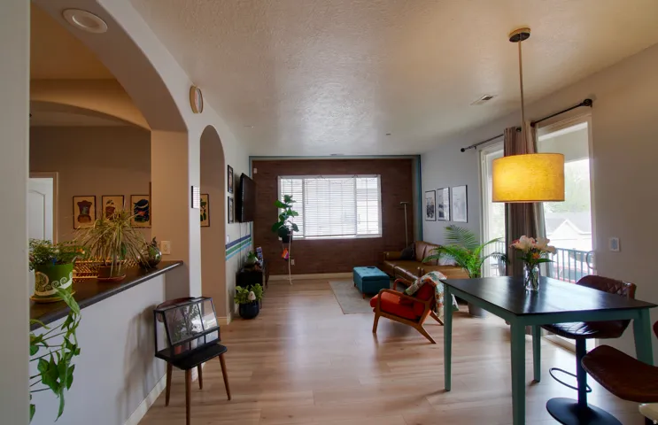 Living room featuring a textured ceiling, light wood-style flooring, brick wall, and arched walkways