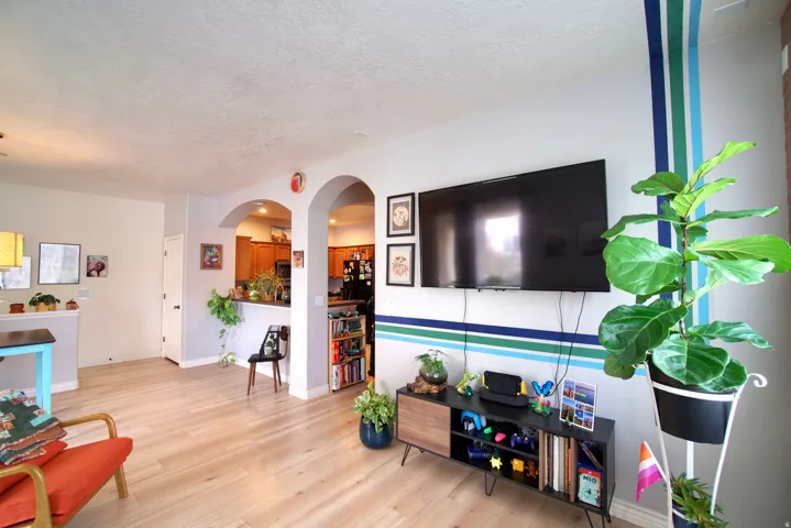Living area featuring arched walkways, light wood-style floors, and a textured ceiling