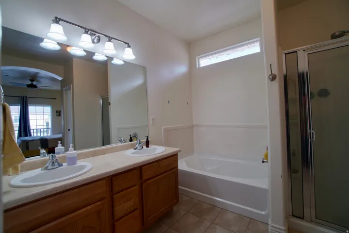 Ensuite bathroom with healthy amount of natural light, a shower stall, double vanity, and a bath
