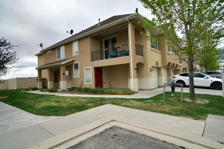 View of front of property with a balcony, stucco siding, and a front lawn