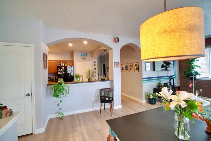 Dining space featuring light wood-type flooring, a textured ceiling, and arched walkways