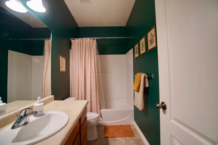 Full bathroom featuring vanity, light tile patterned floors, shower / tub combo, and a textured ceiling