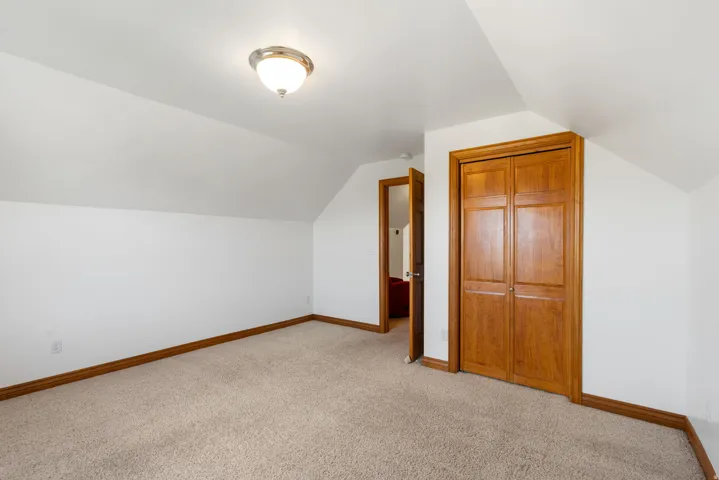 Bonus room with light carpet and vaulted ceiling