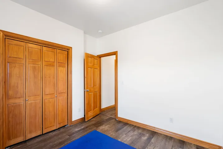 Unfurnished bedroom with a closet and dark wood-style flooring