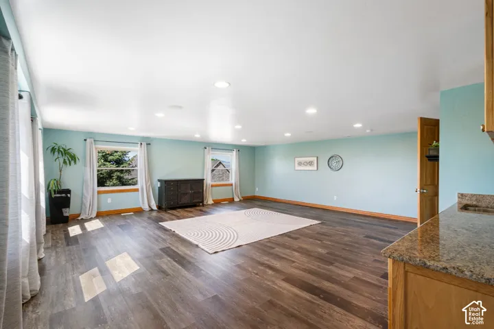 Unfurnished living room featuring recessed lighting and dark wood-style flooring