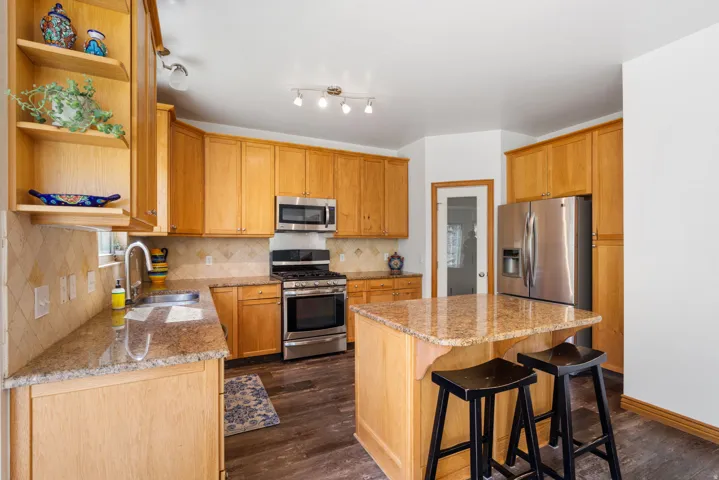 Kitchen with granite countertop, stainless steel appliances, and ample storage