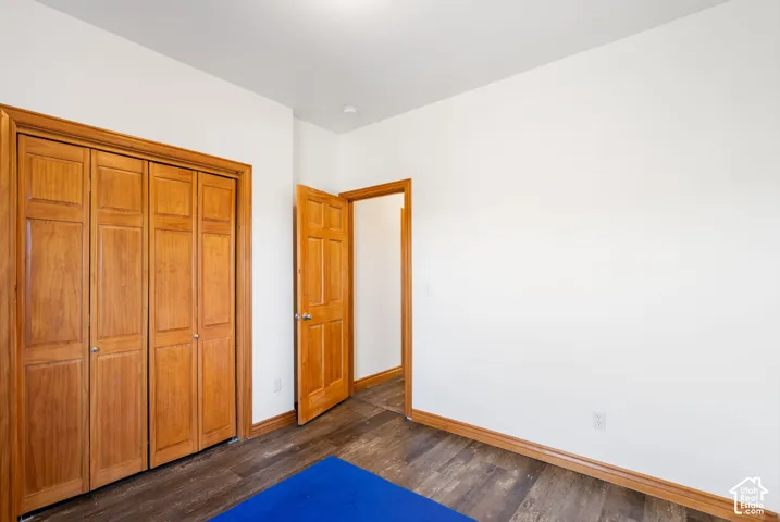 Unfurnished bedroom with a closet and dark wood-style flooring