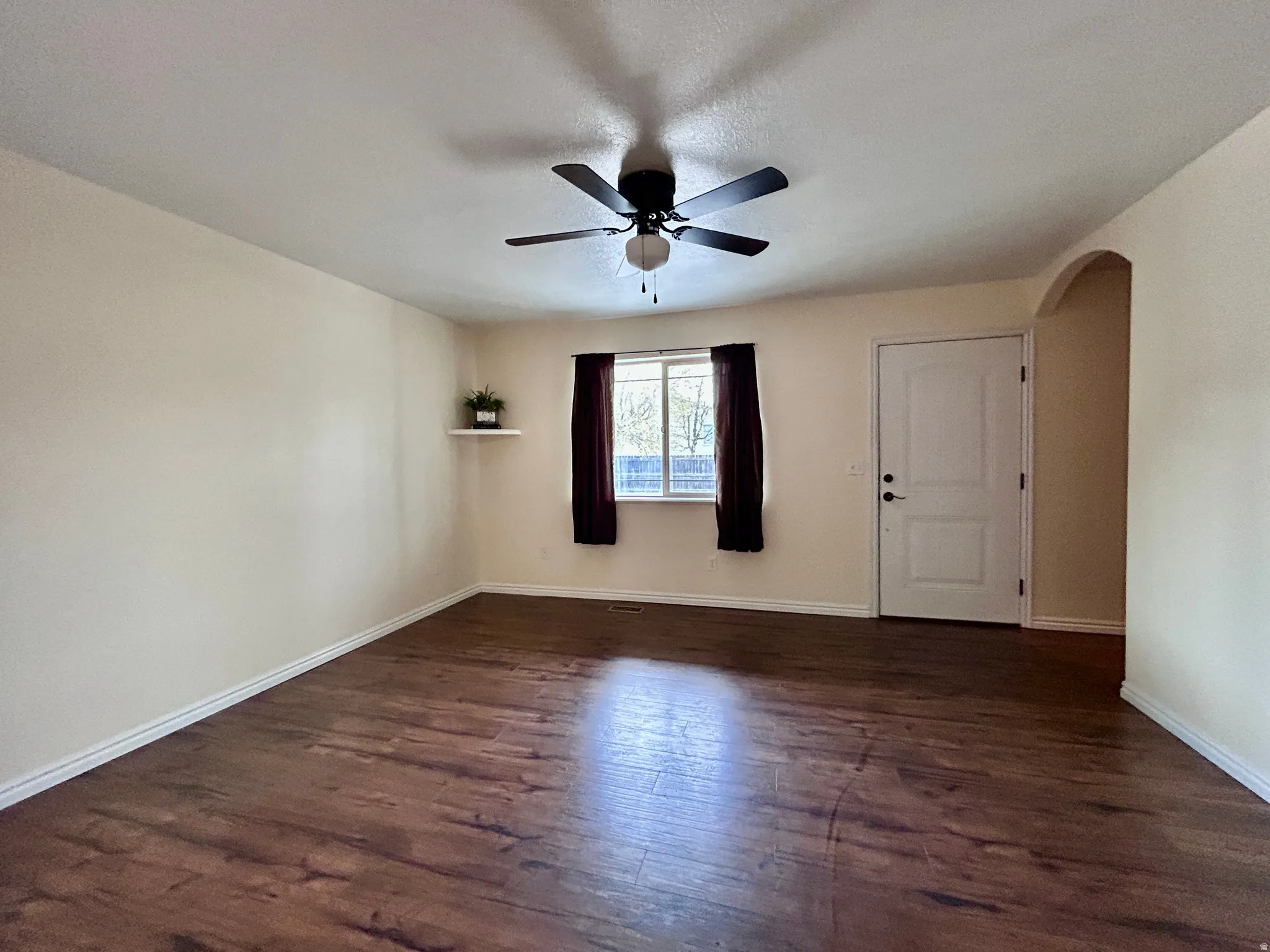 Living room with laminate flooring and archway to the second floor.