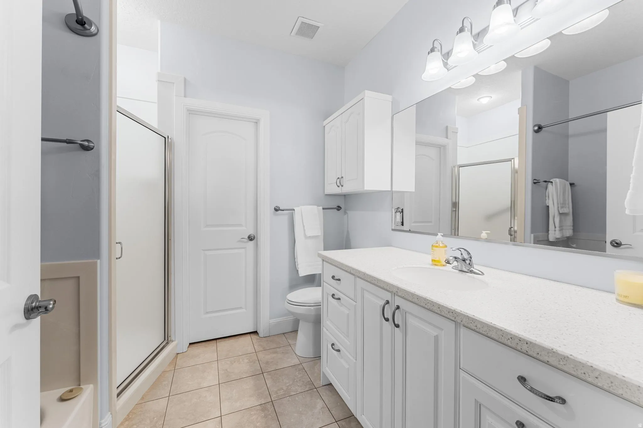 Main Bathroom with corain countertops and tile floors. Door leads to walk in closet