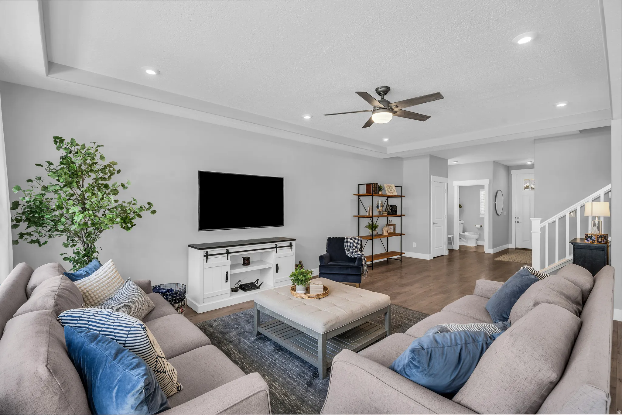 Living room with ceiling fan, wood finished floors, recessed lighting, and a tray ceiling
