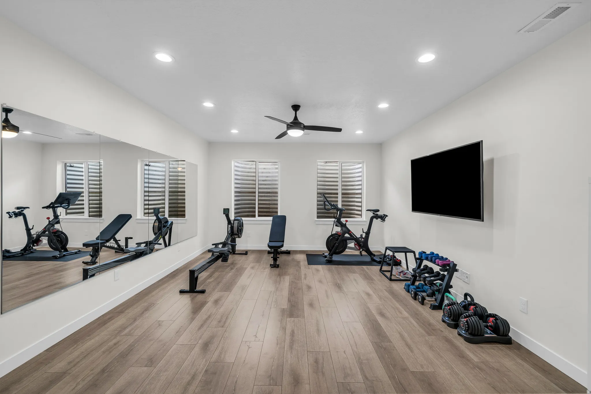 Workout area with a ceiling fan, light wood-style floors, and recessed lighting