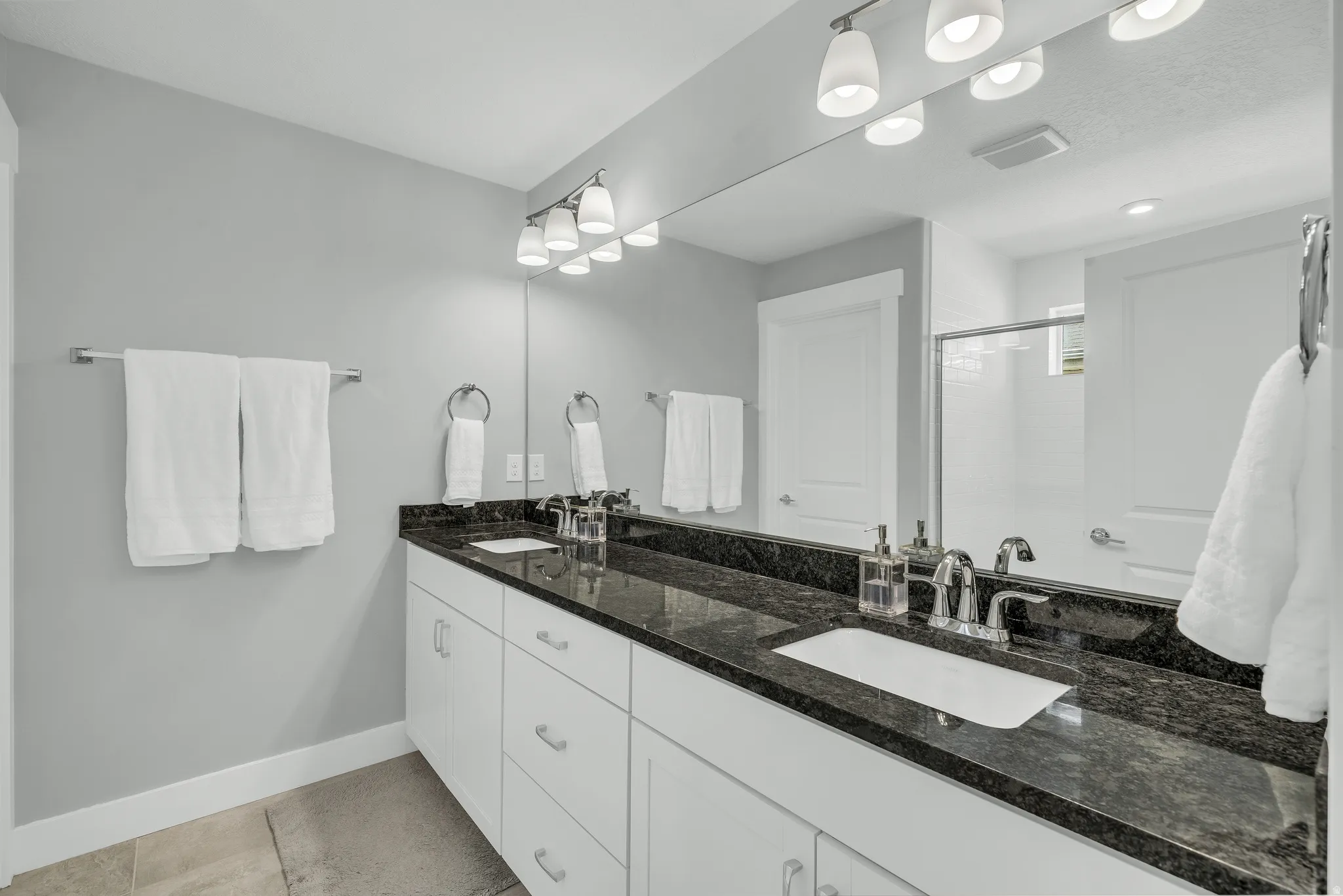 Full bathroom with double vanity and a stall shower