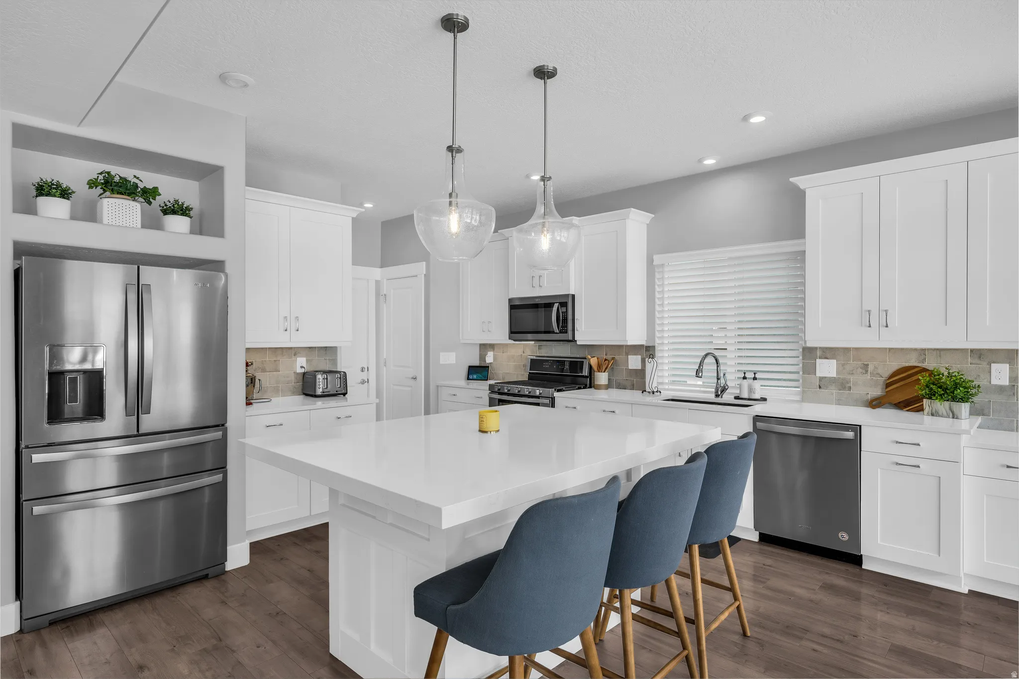 Kitchen featuring stainless steel appliances, white cabinetry, a kitchen island, open shelves, and pendant lighting