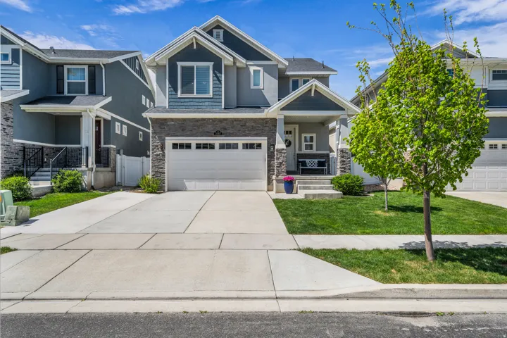 Craftsman house with a garage, stone siding, driveway, and covered porch