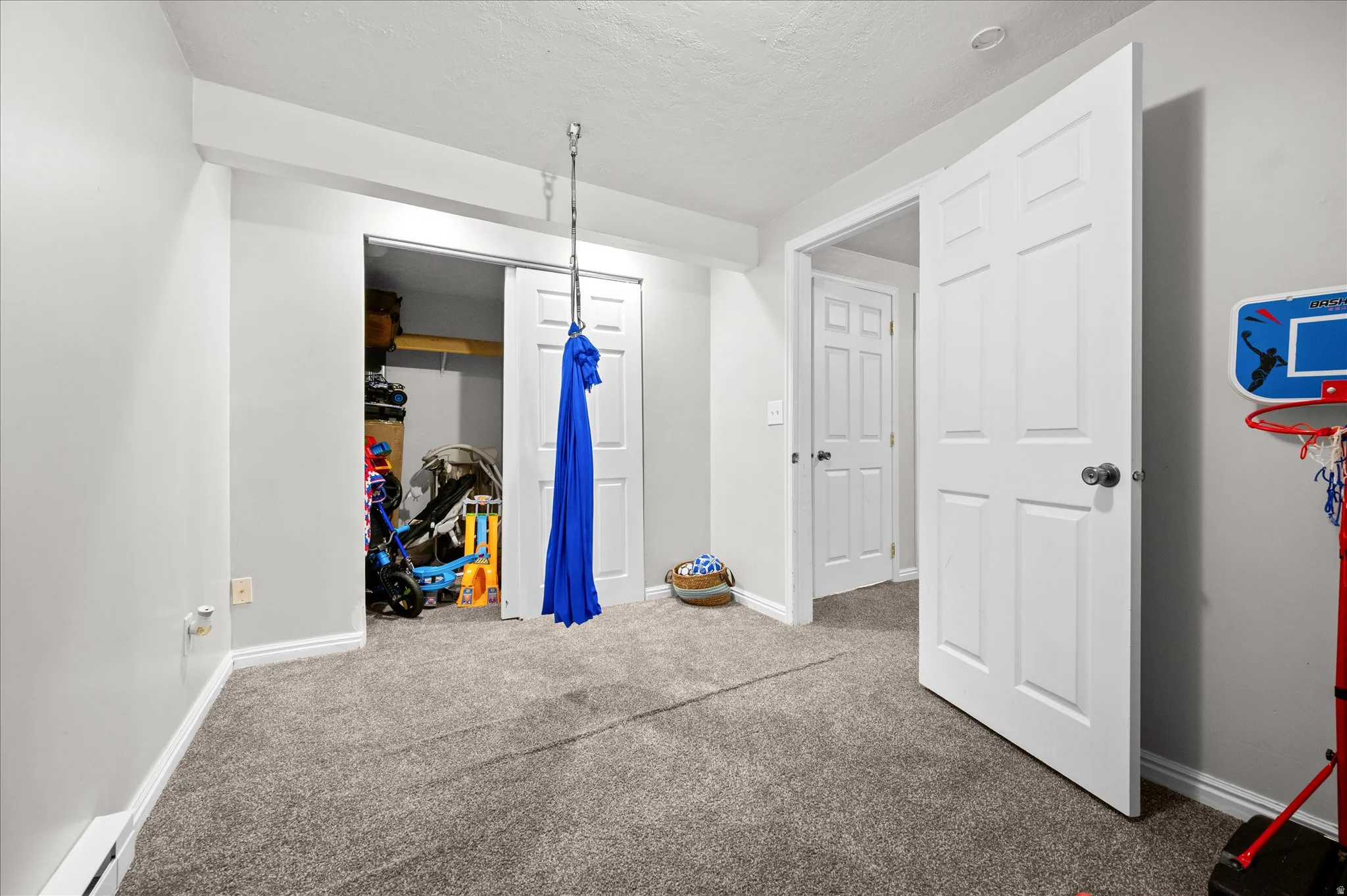 Bedroom featuring a closet, carpet, a baseboard radiator, and a textured ceiling