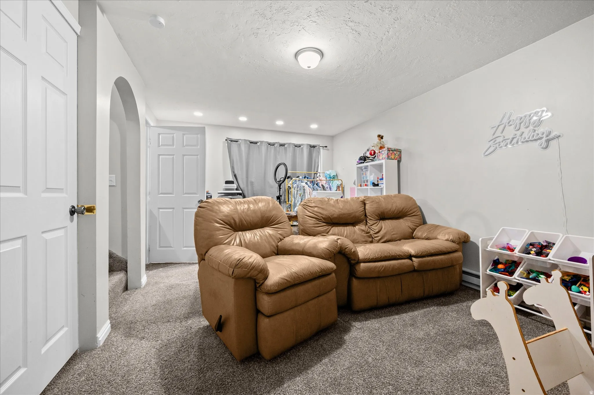 Carpeted bedroom with arched walkways, a textured ceiling, and recessed lighting
