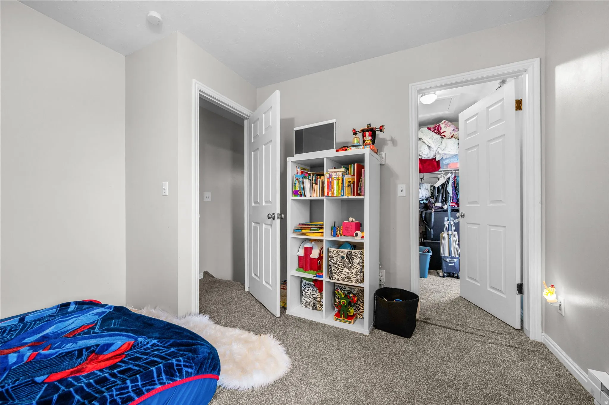 Bedroom with light colored carpet and a spacious closet
