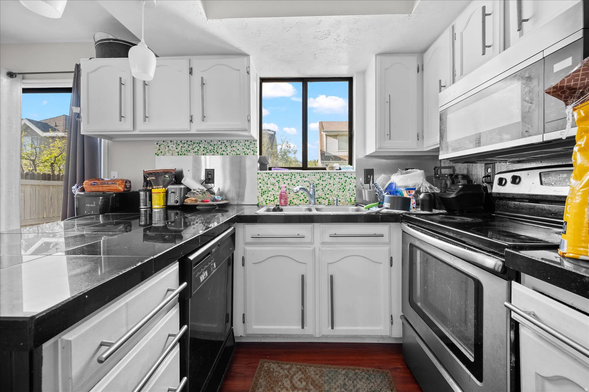 Kitchen featuring stainless steel range with electric cooktop, white cabinets, and tile counters