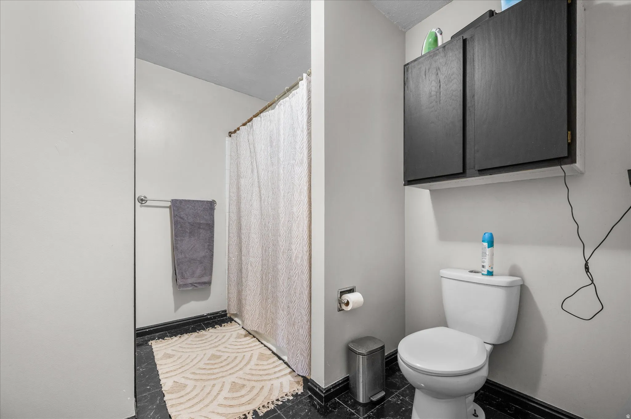 Full bath featuring curtained shower and a textured ceiling